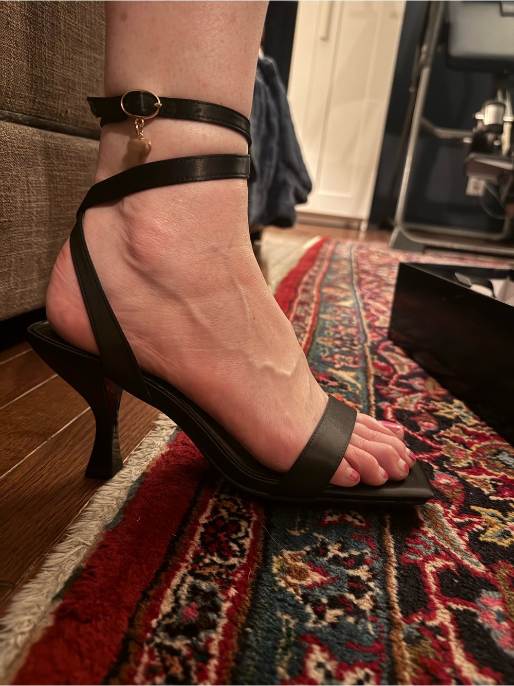 Black square heel satin sandal with ankle strap and heart charm.